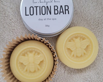 May include: Two round lotion bars with a bee design, packaged in a silver tin with the label "Lisa's Backyard Bees Lotion Bar, Day at the Spa, 38g".