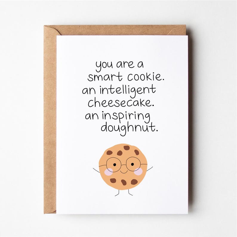 May include: A white card with brown text that reads "You are a smart cookie. An intelligent cheesecake. An inspiring doughnut."  A cartoon cookie with chocolate chips, glasses, and a smile is at the bottom of the card.