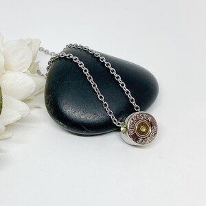 May include: A silver chain necklace with a bullet casing pendant. The casing is engraved with "WINCHESTER" and "30-06 SPRG".