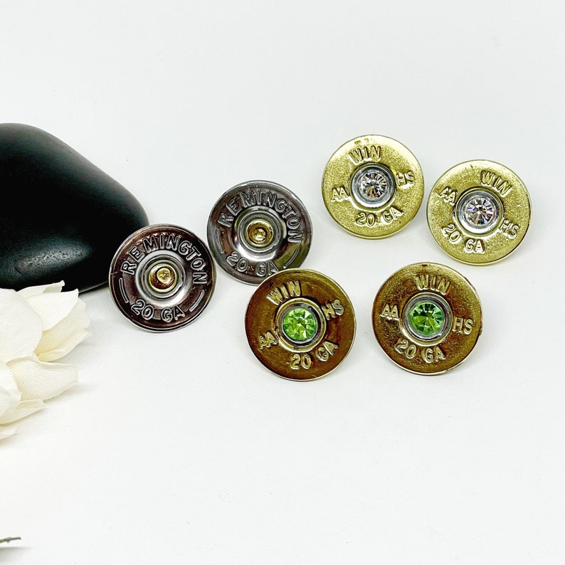 May include: Four pairs of earrings made from shotgun shells with rhinestones. The earrings are in silver, gold, and green.