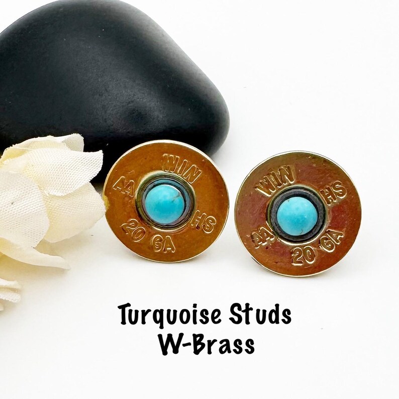 May include: A pair of turquoise stud earrings made from brass shotgun shells. The shells are marked with "WIN" and "20 GA" and have a turquoise stone in the center.