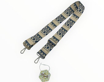 May include: A beige and blue patterned adjustable strap with silver metal clasps. The strap has a geometric pattern and is attached to a small tag that says "Manbi".
