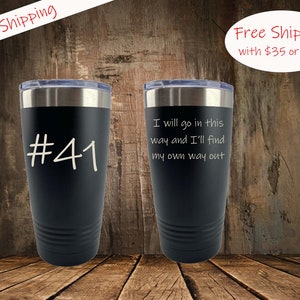May include: Two black stainless steel tumblers with white text. The tumbler on the left has the number "#41" on it. The tumbler on the right has the text "I will go in this way and I'll find my own way out".