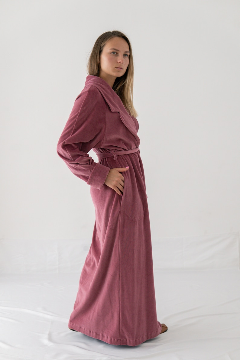 Puede incluir: Una bata larga de terciopelo rosa con cuello chal y cintur&oacute;n de lazo. La bata tiene un corte holgado y es perfecta para relajarse en casa.