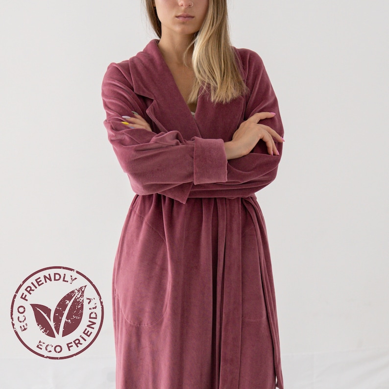 Puede incluir: Una bata larga de color burdeos con cuello chal y cintur&oacute;n de lazo. La bata est&aacute; hecha de una tela suave y mullida. La etiqueta de la bata dice "ECO FRIENDLY".