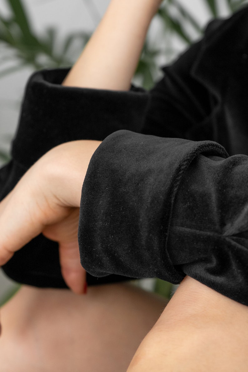 May include: Close-up of a black velvet sleeve with a folded cuff. The fabric is soft and textured.