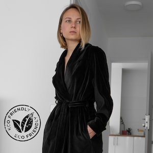 May include: A black velvet robe with a shawl collar and a tie belt. The robe is made of a soft, luxurious fabric and has a relaxed fit.