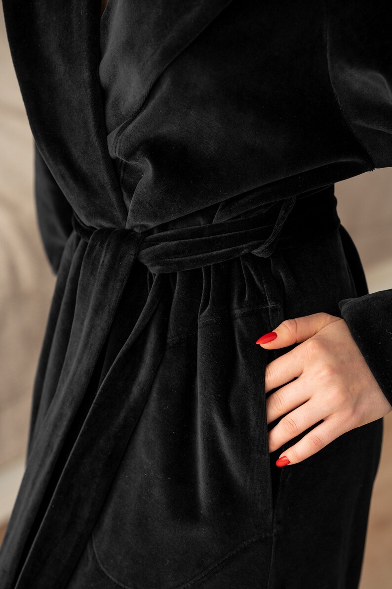 May include: A black velvet robe with a tie belt and a pocket. The robe is made of a soft, luxurious fabric.