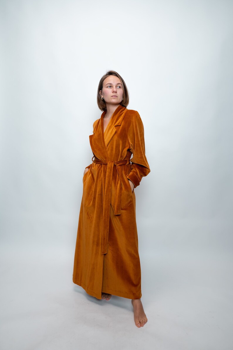May include: A long, rust-colored velvet robe with a shawl collar and a tie belt.