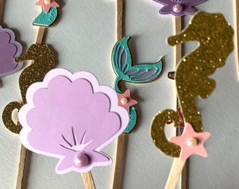 May include: A set of 10 mermaid-themed cake toppers. The toppers feature a variety of sea creatures, including seahorses, seashells, and mermaid tails. The toppers are made of glitter cardstock and are perfect for adding a touch of whimsy to your next mermaid-themed party.