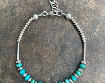 May include: Silver bracelet featuring turquoise beads and small silver beads. The bracelet has a delicate chain with a lobster clasp and an adjustable length. The turquoise beads are a mix of light and dark blue-green hues, creating a natural, earthy look.