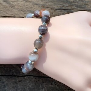 May include: A bracelet made of brown, white, and gray agate beads with silver spacers.