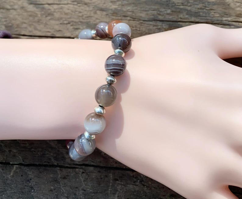 May include: A bracelet made of brown, white, and gray agate beads with silver spacers.
