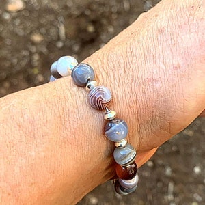 May include: A bracelet made with gray, white, and brown agate beads with silver spacers.