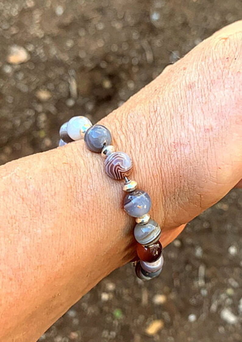 May include: A bracelet made with gray, white, and brown agate beads with silver spacers.
