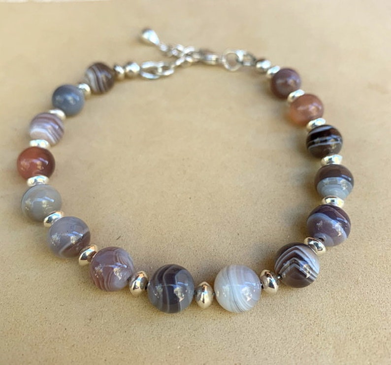 May include: A bracelet made with brown, gray, and white agate beads and silver spacers.