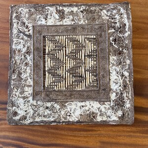 May include: Square decorative tray with a woven center and a textured, mottled border. The center features a woven pattern of light and dark brown reeds. The border has a rough, off-white and brown appearance.