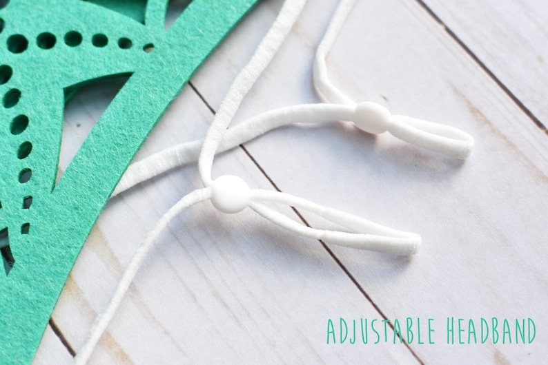 May include: Close-up of a white adjustable headband with white plastic sliders. The headband is made of elastic material and is designed to fit comfortably around the head. "ADJUSTABLE HEADBAND" is written in green text below the headband.