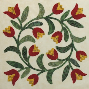 Peut inclure: Un bloc de courtepointe de style vintage avec un motif floral composé de tulipes rouges et de feuilles vertes. Les tulipes ont un centre jaune et sont disposées en cercle.