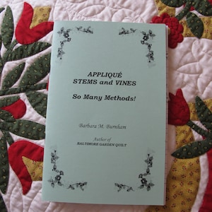 May include: A light blue book with the title "Appliqué Stems and Vines So Many Methods!" by Barbara M. Burnham, author of "Baltimore Garden Quilt".