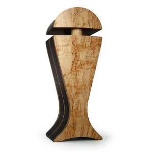 May include: A wooden decorative vase with a unique design. The vase is made of light wood with dark brown accents and has a rounded top and a wide base.