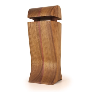 K&ouml;nnte beinhalten: Eine Holzkiste mit einem geschwungenen Design und einem kontrastierenden roten Streifen. Die Kiste hat einen Klappdeckel und eine glatte Oberfl&auml;che.