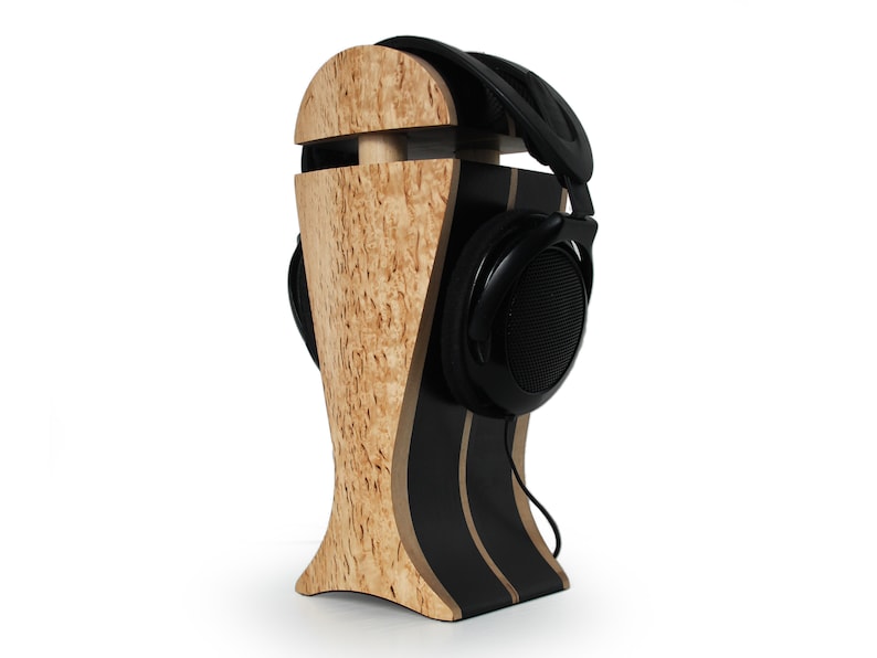 May include: A wooden headphone stand with a black and brown striped base. The stand is shaped like a head and has a black headphone resting on it.