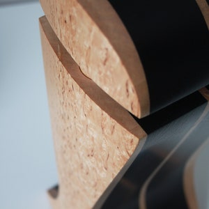 May include: Close-up of a wooden box with a black and brown striped lid. The box is made of a light wood with a unique grain pattern.