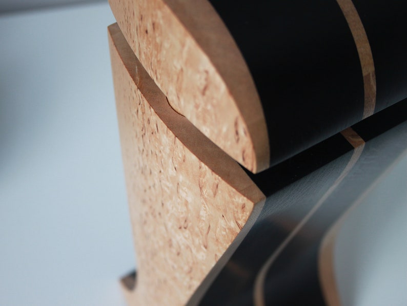 May include: Close-up of a wooden box with a black and brown striped lid. The box is made of a light wood with a unique grain pattern.