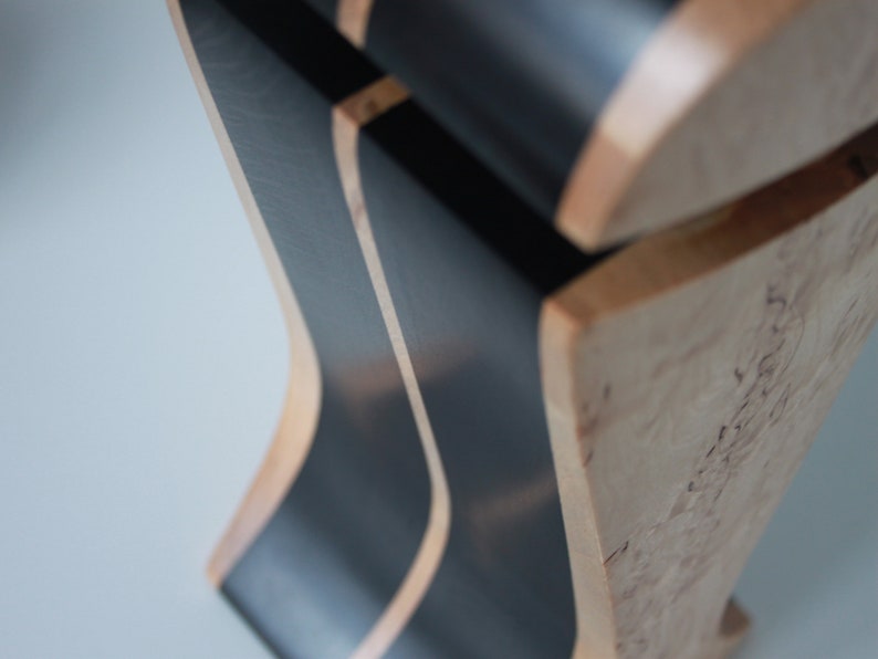 May include: Close-up of a wooden sculpture with black painted stripes. The wood has a natural grain pattern and the black paint is smooth.