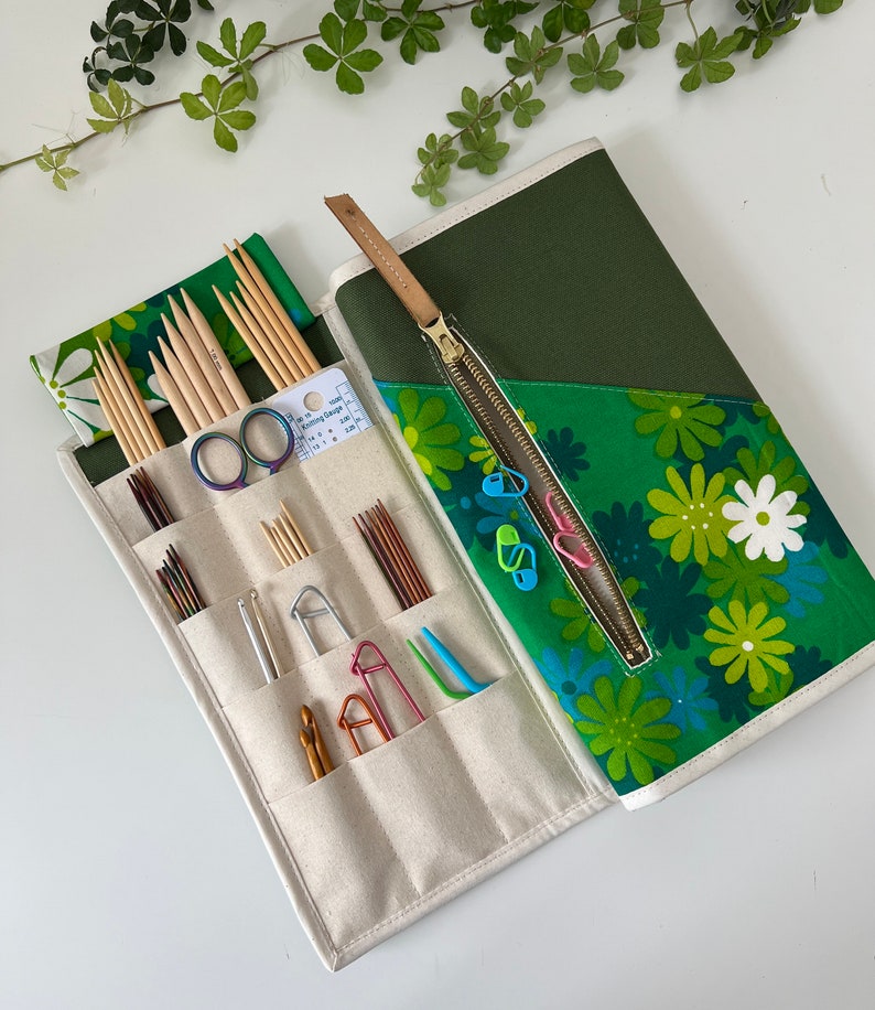 Pode incluir: Um estojo de tecido para organizar agulhas de tric&ocirc; com estampa floral verde e interior creme com v&aacute;rios bolsos. Cont&eacute;m agulhas de madeira, agulhas de croch&ecirc; de metal, marcadores de pontos, uma tesoura e uma ferramenta de calibre.