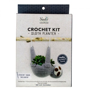 May include: Crochet kit to make a gray sloth planter. The kit includes a crochet hook and instructions. The finished planter is 11 1/2 inches wide by 9 1/4 inches tall by 4 inches deep. The sloth planter is hanging from a branch and has a small plant inside. The text on the box says "Crochet Kit - Sloth Planter - Hello, my name is Stevie".