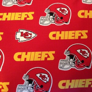 May include: Red fabric with a repeating pattern of a football helmet, a red arrow with the letters KC, and the word "CHIEFS" in yellow.