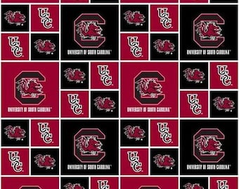Könnte beinhalten: Ein roter und schwarzer Stoff mit einem sich wiederholenden Muster des Logos der University of South Carolina. Das Logo zeigt ein granatfarbenes 'C' mit einem Kampfhahn darin. Der Text 'University of South Carolina' steht unter dem Logo.
