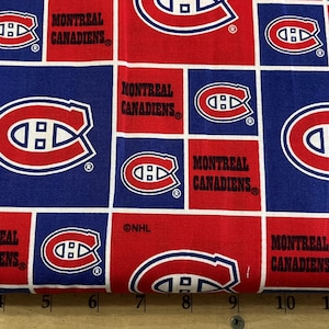 May include: Red and blue fabric with a repeating pattern of the Montreal Canadiens hockey team logo. The logo is a red and white stylized "C" with a hockey stick inside. The text "Montreal Canadiens" is printed in black below the logo.