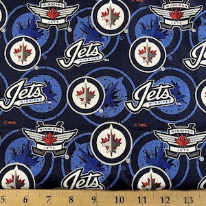 May include: Blue fabric with a repeating pattern of white hockey logos. The logos feature a stylized jet plane, the words "Winnipeg Jets", and a hockey team logo. The fabric is perfect for quilting, crafts, and apparel.
