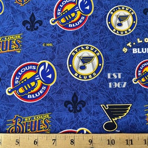 May include: Blue fabric with a repeating pattern of the St. Louis Blues hockey team logo. The logo features a trumpet, a note, and the words "St. Louis Blues". The fabric also includes the team's founding year, "Est. 1967".