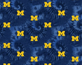 May include: A blue and white tie-dye fabric with a repeating pattern of yellow "M" letters.