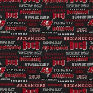 May include: A black and red fabric with a repeating pattern of the Tampa Bay Buccaneers logo and the words "Tampa Bay Buccaneers" and "Bucs".