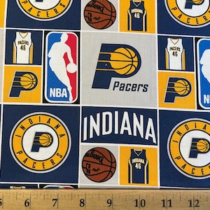 May include: A blue and yellow fabric with a repeating pattern of the Indiana Pacers logo, basketballs, and jerseys. The text "Indiana Pacers" is repeated throughout the fabric.