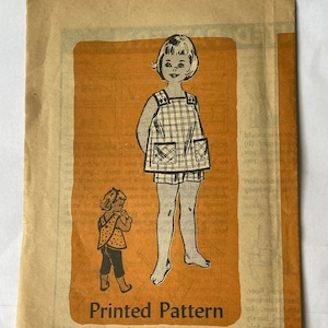 Op de afbeelding: Vintage naaipatroon voor een kinderjurk en een broekje. Het patroon is gedrukt op geel papier met een zwart-witte illustratie van een meisje dat de outfit draagt. Het patroonnummer is 4707 en de maat is 6.