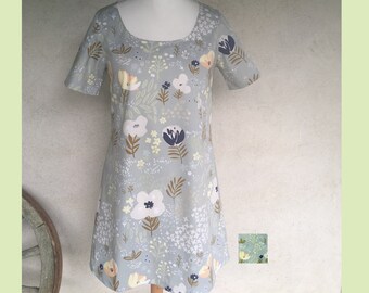 Loose A line dress with short sleeves and round neckline made in a floral fabric in shades of green gray