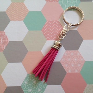 Porte-clés monté sur un large anneau en métal argenté et son pompon fantaisie rose framboise