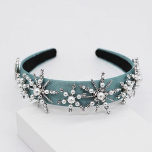May include: A teal blue headband with five silver snowflake-shaped embellishments with pearl accents.