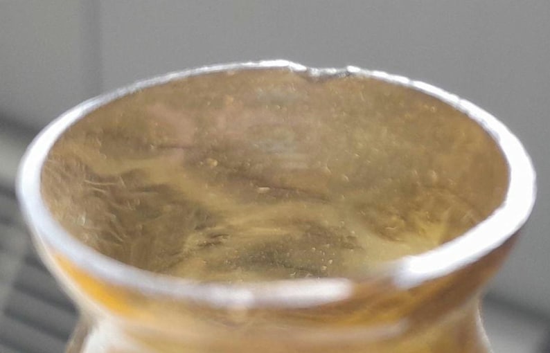 May include: Close-up of the inside of a clear glass bottle with a slightly yellowed tint. The bottle has a round opening and a smooth, slightly textured surface.