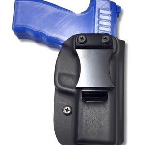 May include: A black leather holster with a silver metal clip and a screw on the side. A blue plastic gun is partially visible in the holster.