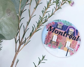 May include: A round button with a colorful illustration of a house with the word "Montreal" and the street name "Mont Royal" on it.