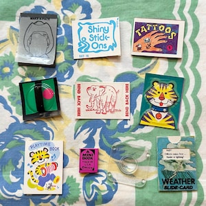 May include: Assortment of vintage stickers featuring various themes, including animals, tattoos, and a make-a-face activity. The stickers are colorful and feature bright illustrations.  The stickers are on a white background with a green floral pattern.