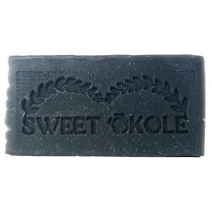 May include: A dark gray bar of soap with the words "SWEET ÖKOLE" embossed on it. The soap is surrounded by a wreath of leaves.