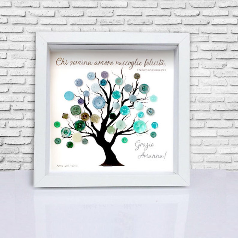 May include: A white framed picture with a black silhouette of a tree with blue, green, and brown buttons on the branches. The quote "Chi semina amore raccoglie felicita." is written on the top of the picture. The words "Grazie Arianna!" are written at the bottom of the picture.